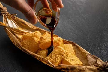 竹皮に盛られたきな粉の生わらび餅と黒蜜
